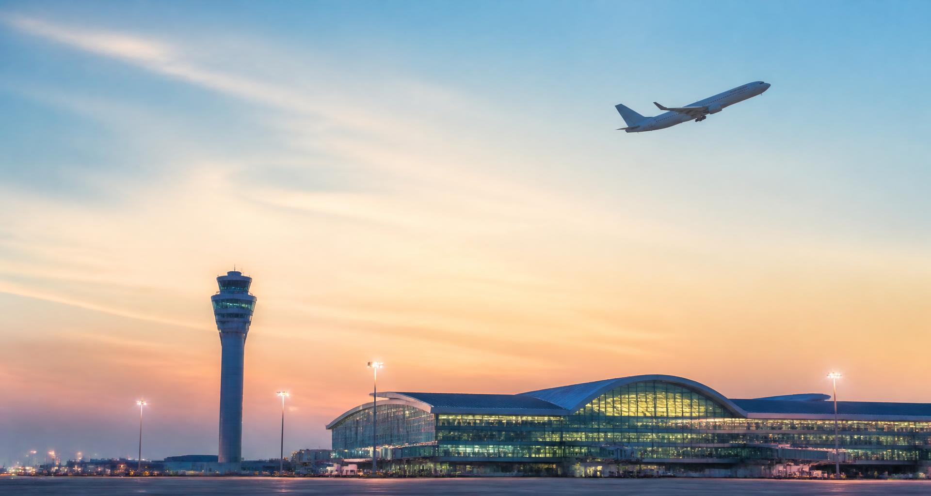 Modern airport terminal skyline at dawn with an airplane taking off